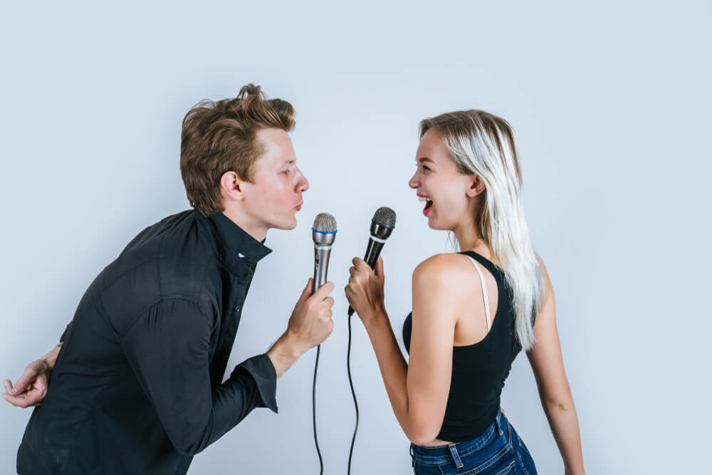 Happy portrait of Couple holding microphone and singing.