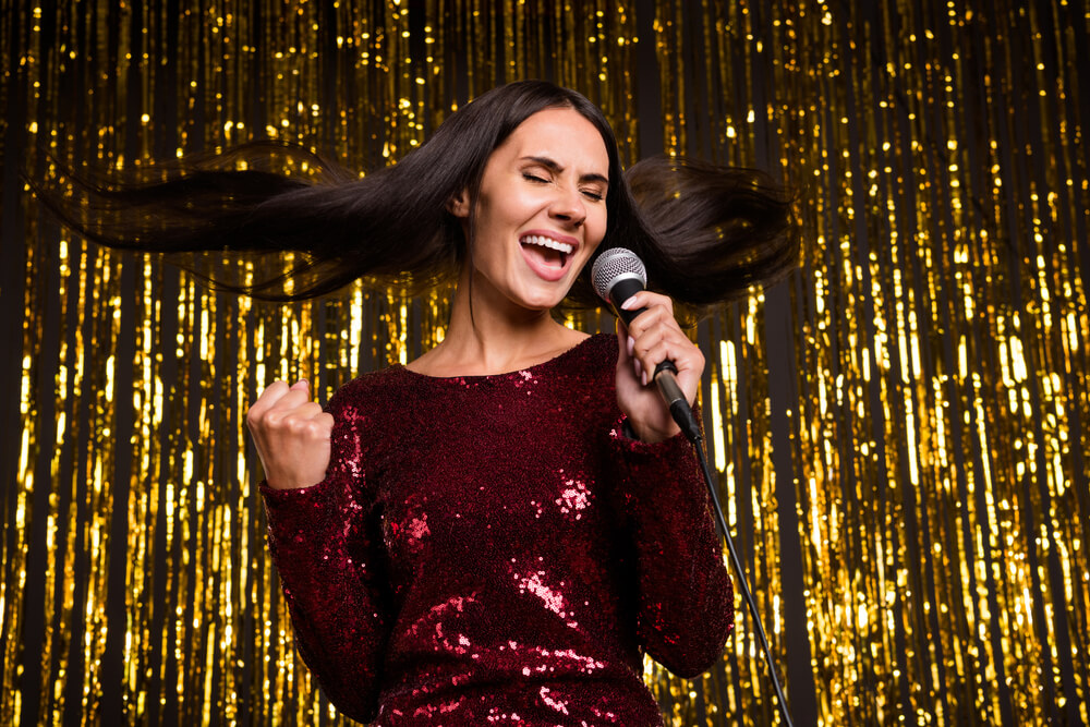 Photo of nice optimistic brunette hairdo lady sing in mic wear red dress isolated on shiny gold color background