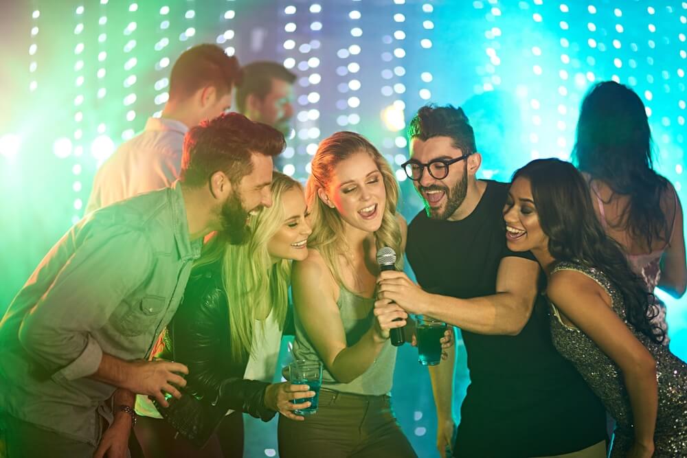 Shot of a group of friends singing karaoke at a party.