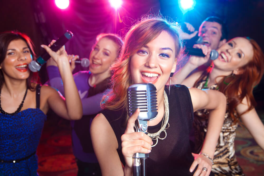 Young girl singing into microphone at party.