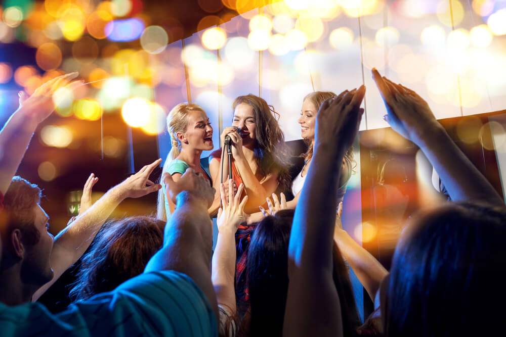 Young women singing karaoke at the club.