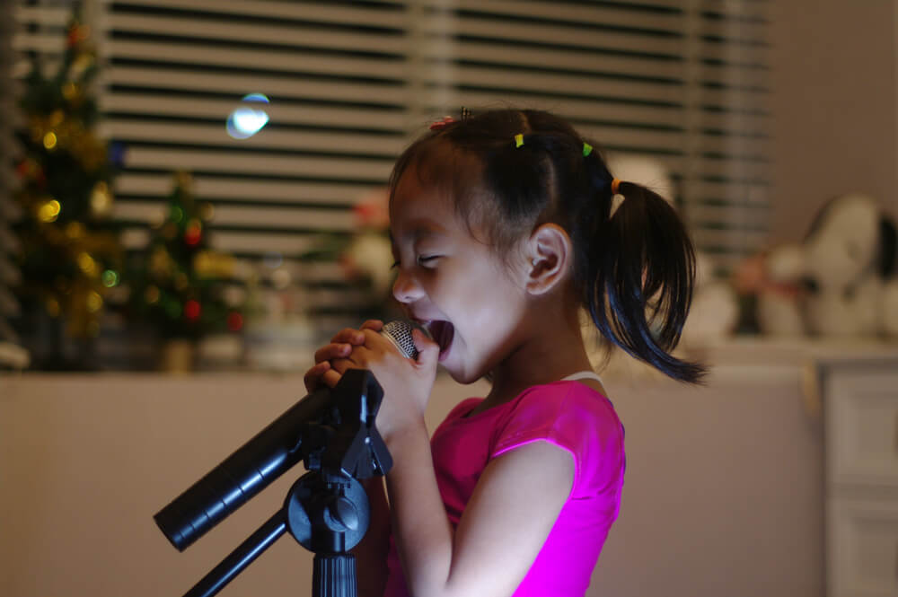 A girl sings joyfully on a microphone.