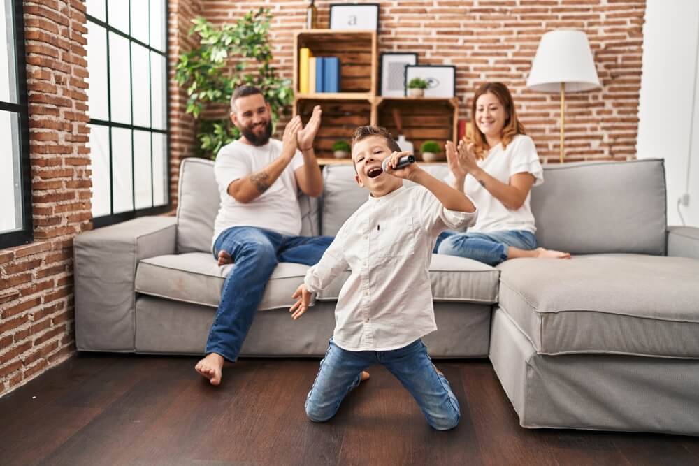 Parents cheer their son while he sings karaoke.