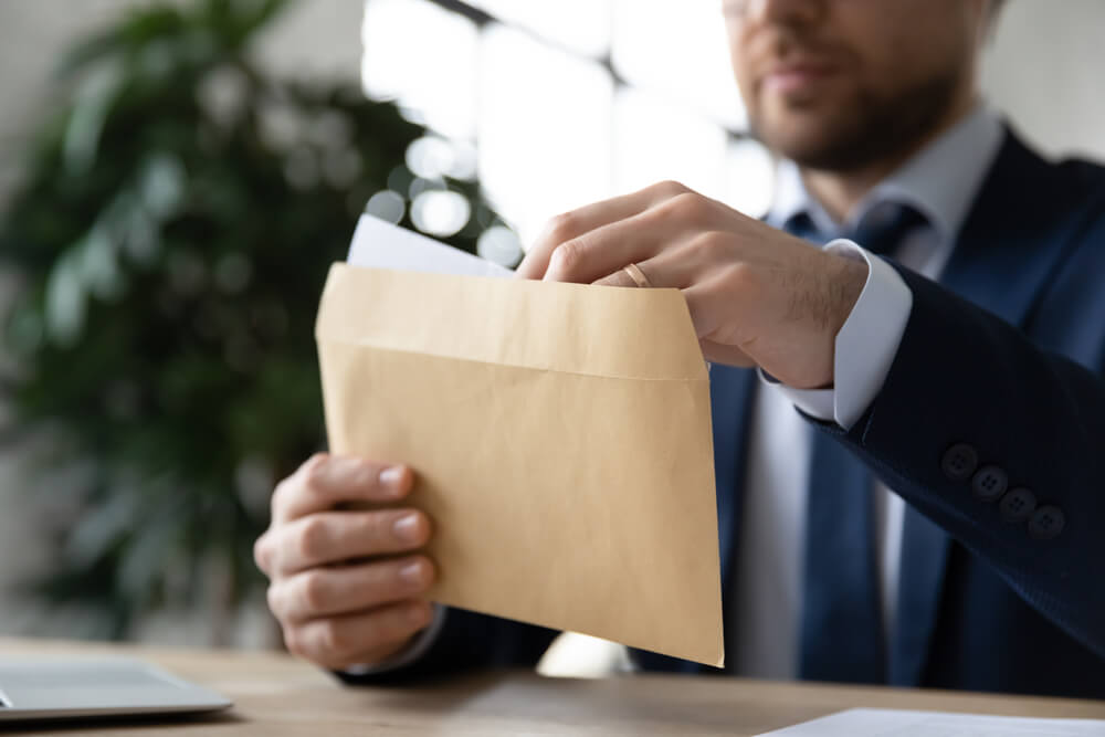 Close up businessman wearing suit holding an envelope.