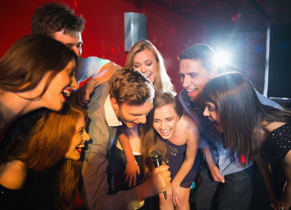 Happy friends singing karaoke together in a bar.