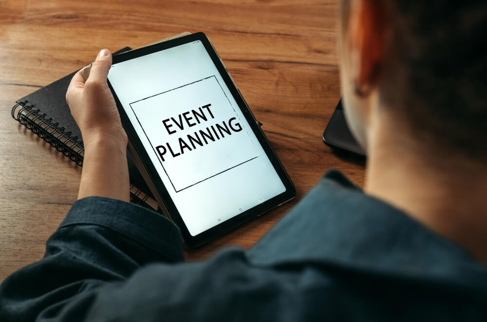 A woman holds a tablet in her hands on the screen of which it is written - Event Planning.