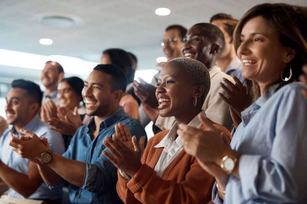 A business team clapping as an audience at a conference or seminar.