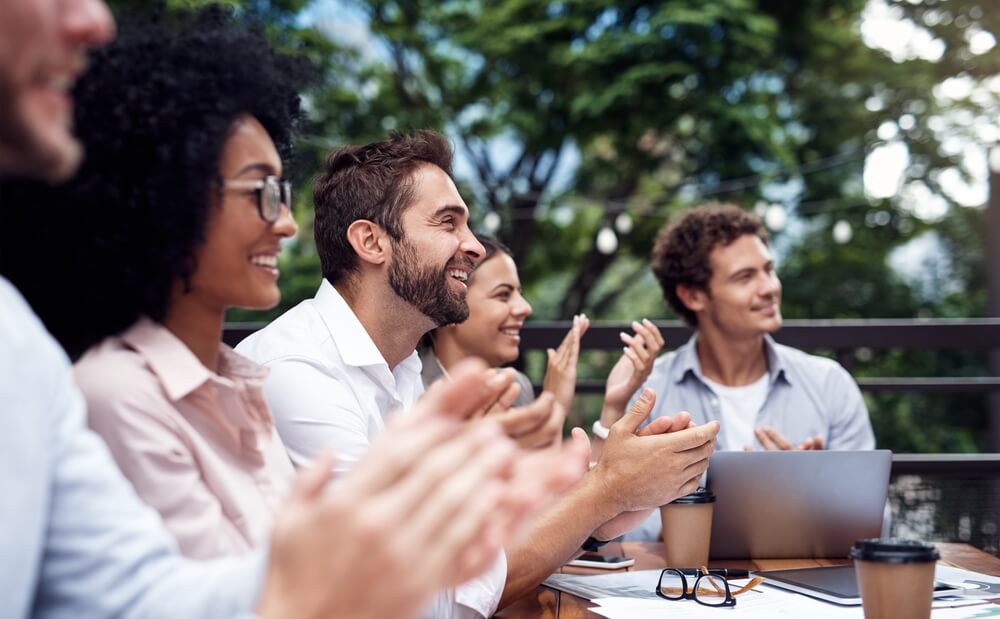 Business people in a cafe applauding and celebrating success during a corporate retreat.