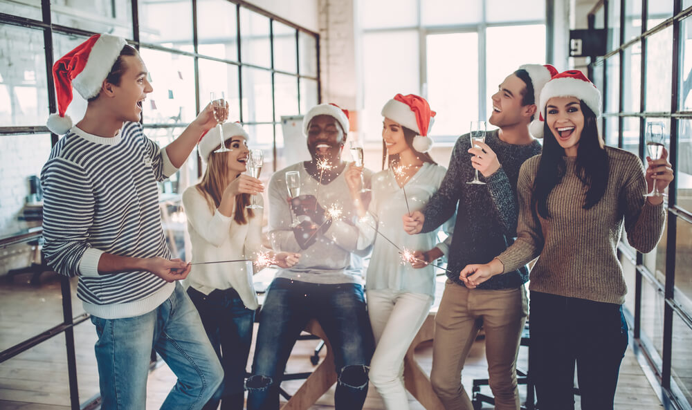 Group of young business people celebrating holidays in modern office.