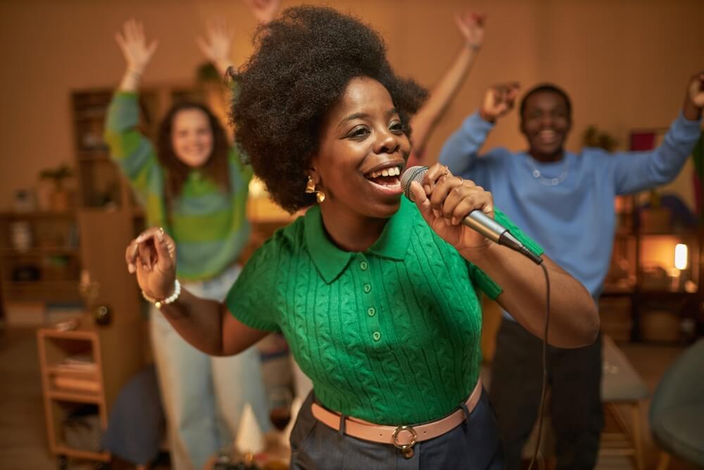 A woman singing to microphone and dancing enjoying karaoke.