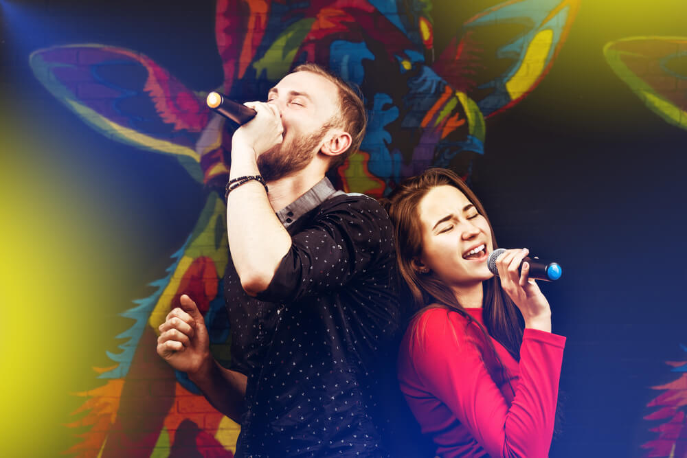 Happy couple singing in karaoke night club.