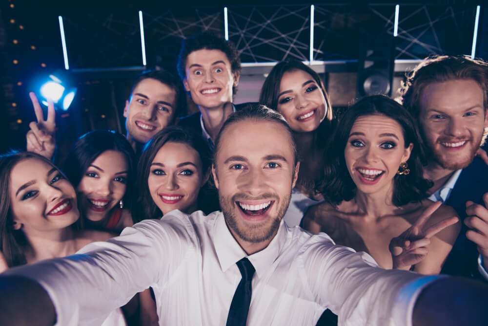 A man making a selfie with his colleagues on a smartphone at the corporate party.